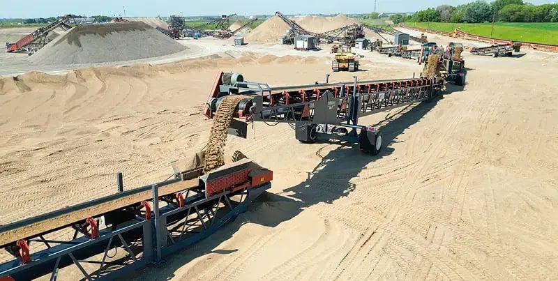Aerial view of a sand and gravel processing facility with long conveyor belt systems transporting materials across the site.