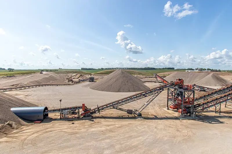 Aerial view of a sand and gravel processing facility with long conveyor belt systems transporting materials across the site.